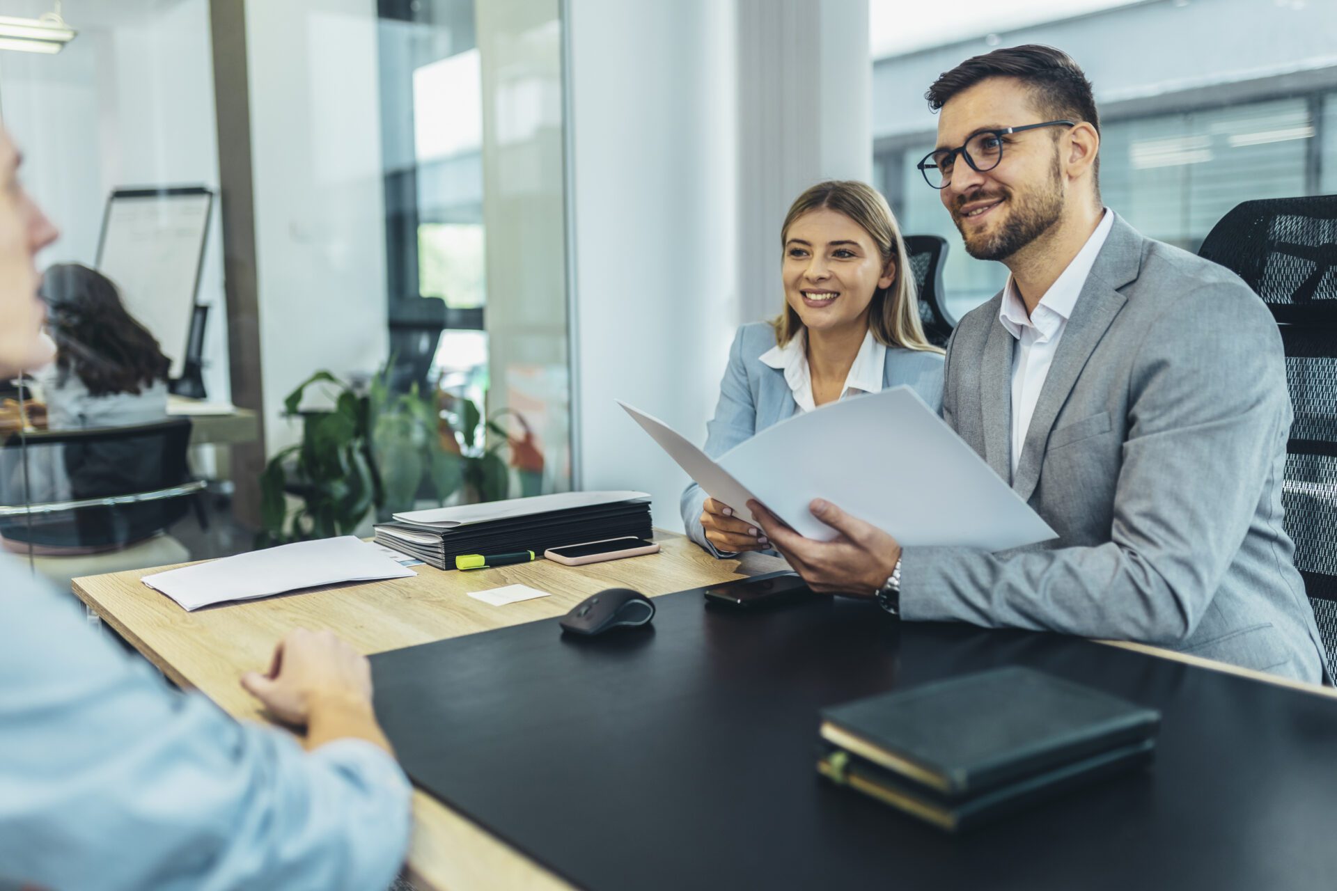 Business meeting with three people discussing documents.